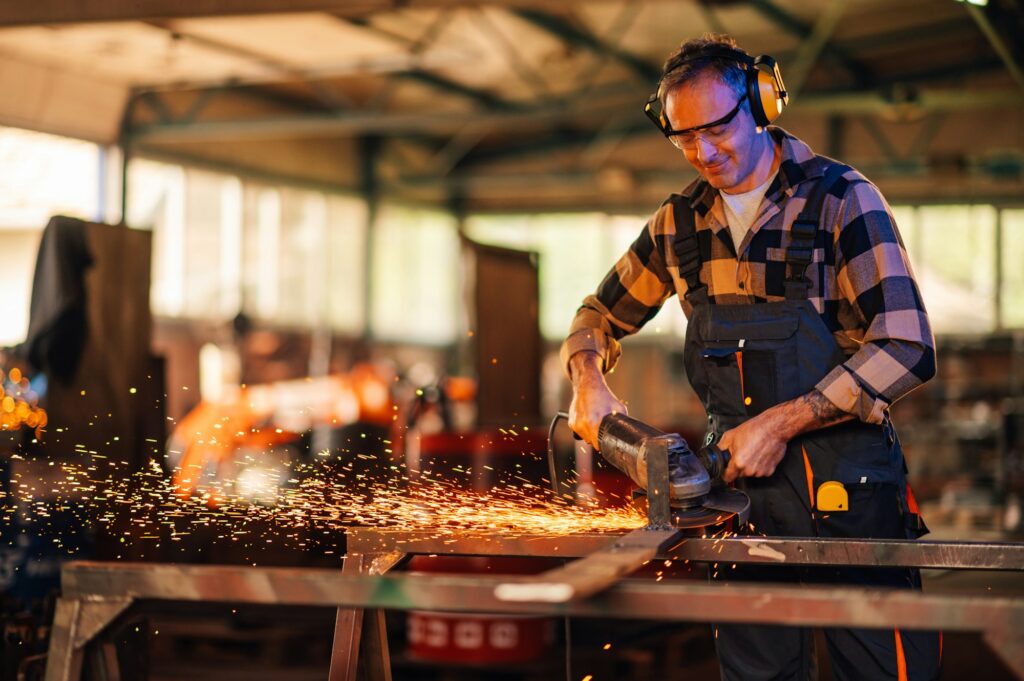 Craftsman patiently grinding metal construction in an indoor facility.